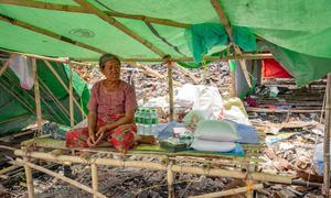 A woman who was affected by the earthquake in Myanmar sits alongside aid items.