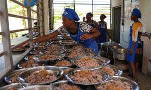 Cooks serve school meals to students in Haiti.