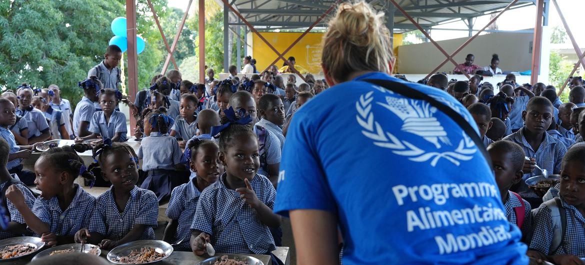 A WFP program worker serves food to a group of school children at a meal in Haiti.