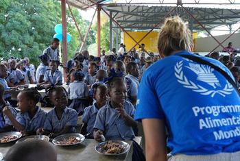 A WFP program worker serves food to a group of school children at a meal in Haiti.
