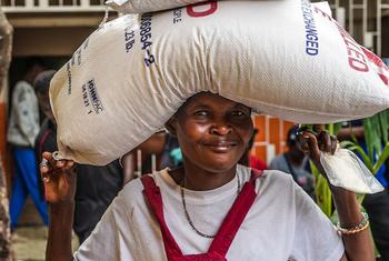 Uma mulher deslocada pela violência carrega um saco de arroz fornecido pela ONU