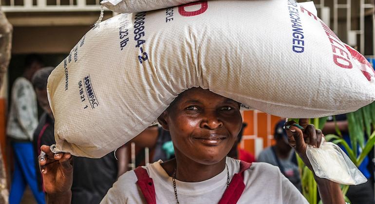 Uma mulher deslocada pela violência carrega um saco de arroz fornecido pela ONU