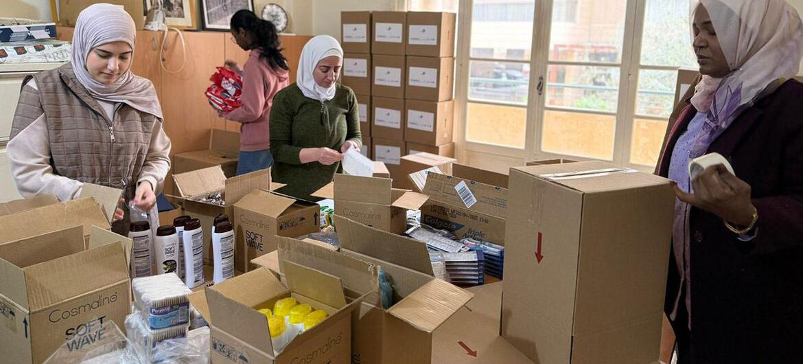 نساء يعبّأن أدوات النظافة في صناديق من الورق المقوى للنساء والفتيات النازحات في لبنان، وهي مبادرة من هيئة الأمم المتحدة للمرأة ومنظمة أسابيل غير الحكومية.