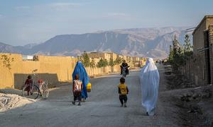 نساء وأطفال يسيرون في الشارع في قرية في شمال أفغانستان.