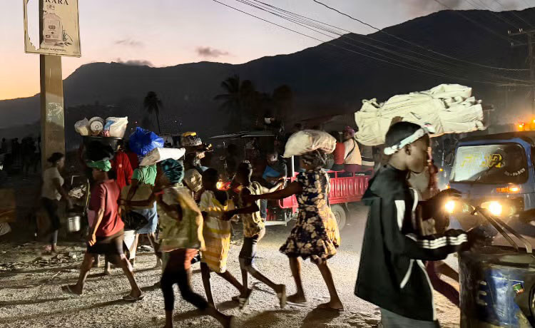 In Haiti, people carrying their belongings flee in near darkness. In Haiti, people carrying their belongings flee in near darkness.