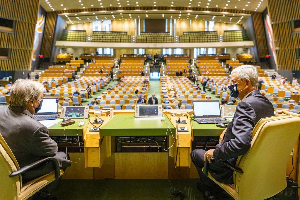 联合国秘书长古特雷斯（左）与联大第75届会议主席博兹克尔戴着口罩在联合国大会堂内交谈。