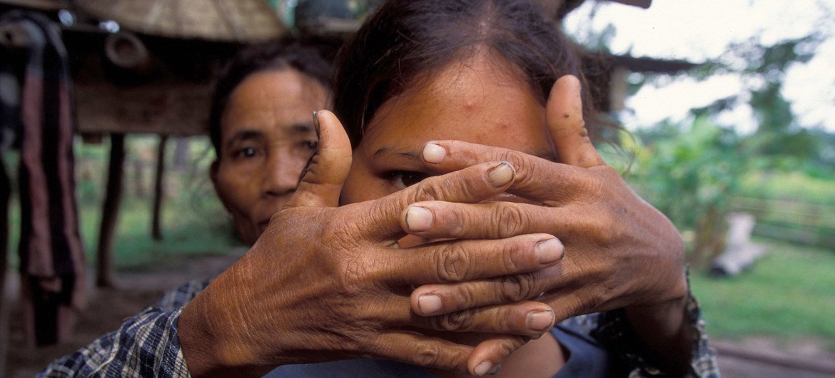 Una madre cubre el rostro de su hija, víctima de la trata a los dieciséis años, para proteger su identidad.