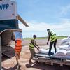À Ouagadougou, au Burkina Faso, des travailleurs humanitaires déchargent des sacs d'aide alimentaire d'un avion du Programme alimentaire mondial ( PAM ) des Nations Unies .
