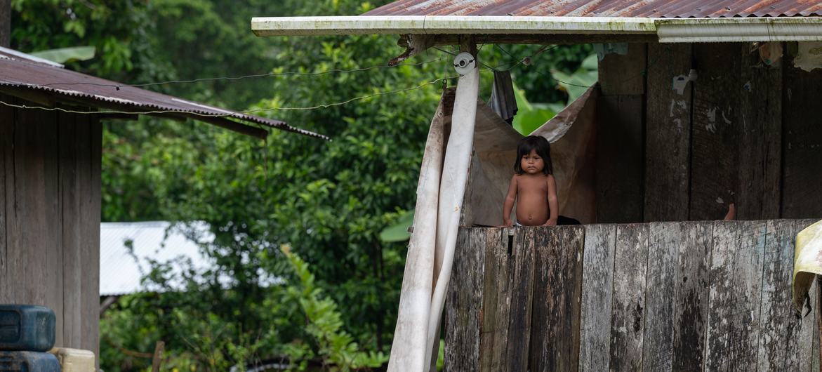 Un joven indígena se encuentra en el balcón de una casa de madera en Litoral del San Juan, Colombia.