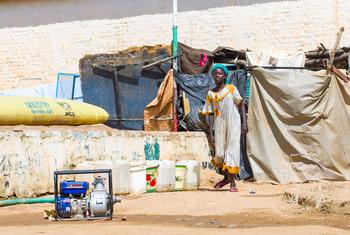 A woman collects water at an IDP camp in Darfur. The war in Sudan has forced millions to flee their homes.