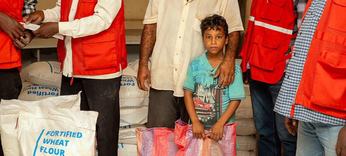 一个流离失所的孩子和他的父亲在苏丹港的一个食品分发点等候。