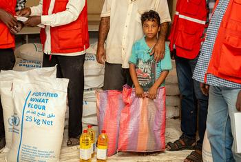 一个流离失所的孩子和他的父亲在苏丹港的一个食品分发点等候。
