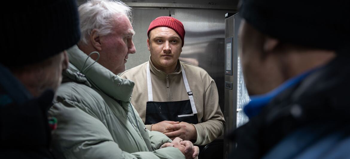 یوکرائن کے شہر بورسپل میں بے گھر افراد کے لیے ایک کھانے کی ٹرک میں فوڈ فار بارڈرز کا ایک انسانی امدادی کارکن شدید سردیوں کے موسم میں گرم کھانا تیار کرتا ہے۔