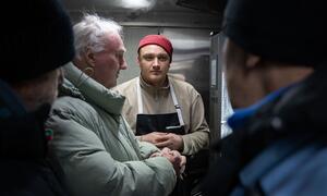 یوکرائن کے شہر بورسپل میں بے گھر افراد کے لیے ایک کھانے کی ٹرک میں فوڈ فار بارڈرز کا ایک انسانی امدادی کارکن شدید سردیوں کے موسم میں گرم کھانا تیار کرتا ہے۔