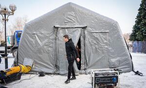 A man walks out of a large grey tent at a heating point in snowy Boryspil, Ukraine.