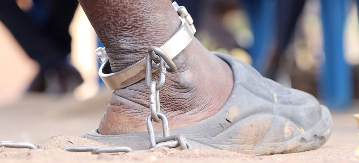 Un primer plano del tobillo de un detenido con una cadena de metal y esposas, que simboliza la llegada de la justicia a través de un tribunal móvil en Sudán del Sur.