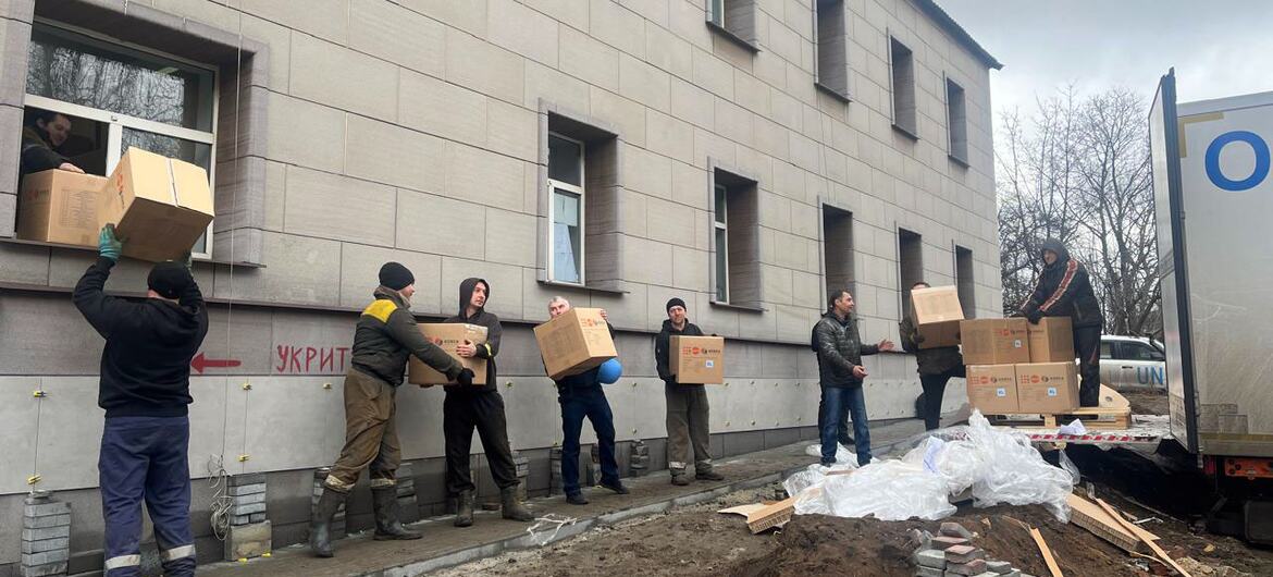 Humanitarian workers unload boxes of aid supplies from a truck to distribute to residents in Dobropillia, Ukraine.