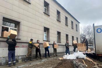 Humanitarian workers unload boxes of aid supplies from a truck to distribute to residents in Dobropillia, Ukraine.