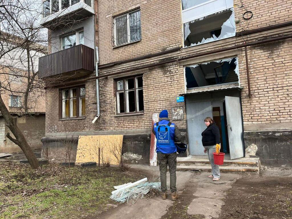 عامل إغاثة إنسانية يتحدث إلى امرأة أمام مبنى سكني متضرر في كريفي ريه، جنوب وسط أوكرانيا.