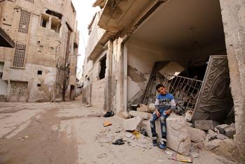 طفل يجلس وسط مبنى مدمر في دوما، الغوطة الشرقية.