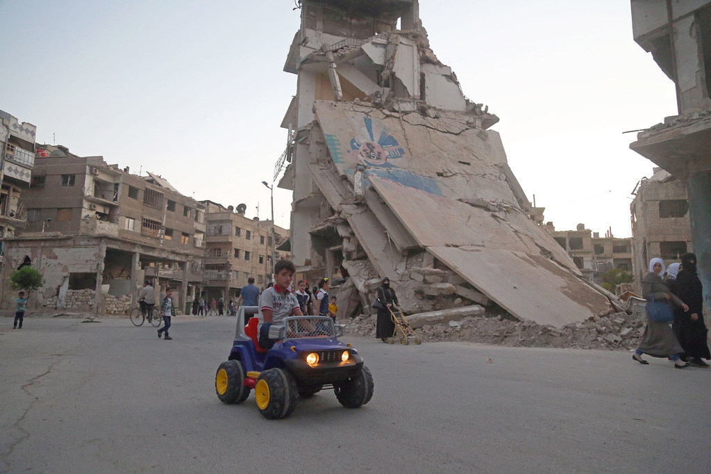 ARCHIVO: Un niño conduce su coche de juguete mientras la gente celebra el Eid al-Fitr, en Ghouta oriental  (Siria).