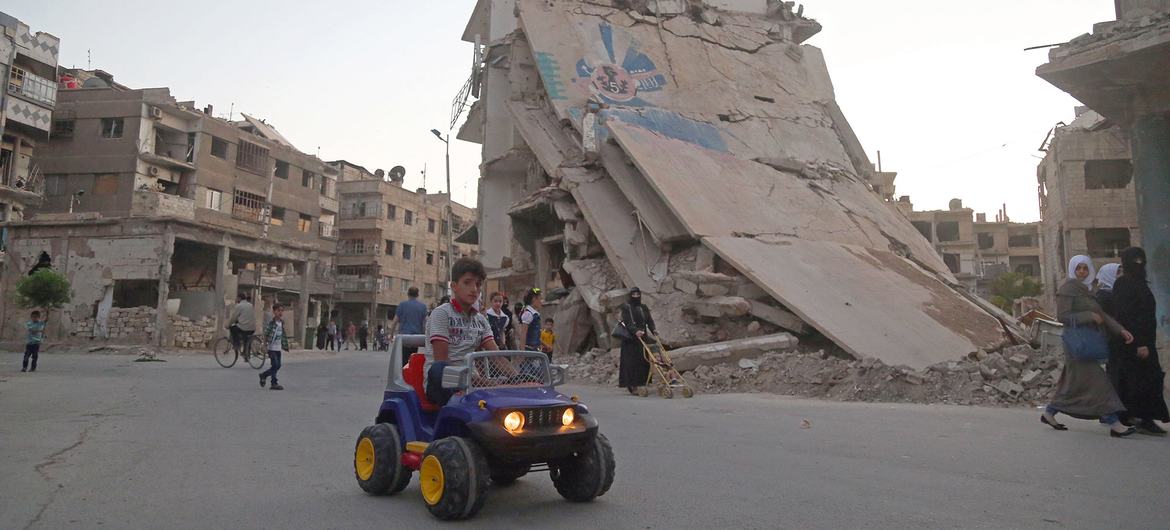 ARCHIVO: Un niño conduce su coche de juguete mientras la gente celebra el Eid al-Fitr, en Ghouta oriental  (Siria).