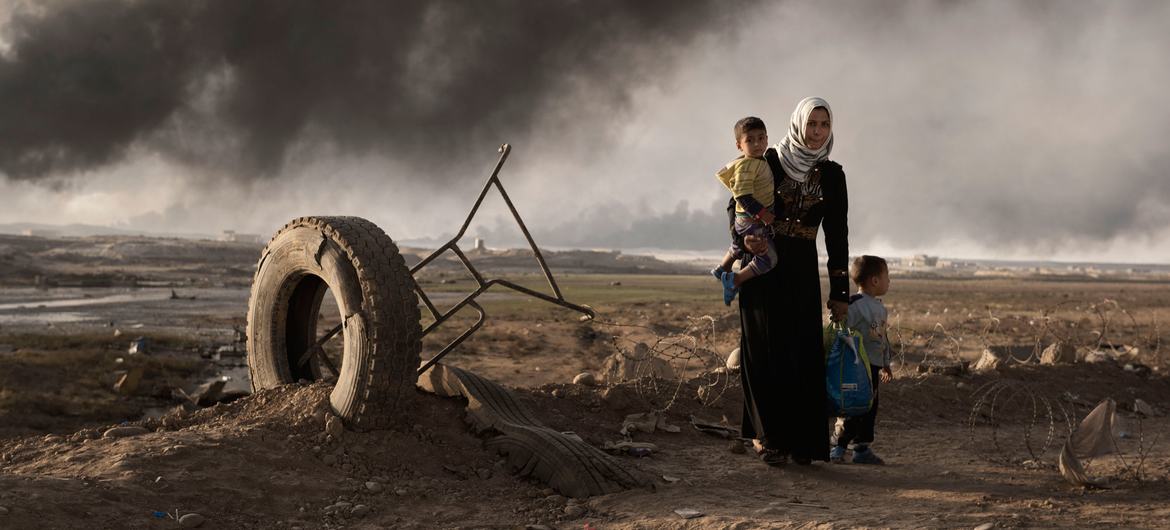 Uma mulher recentemente deslocada caminha com duas crianças num posto de controle em Qayyara, ao sul de Mosul, no Iraque (arquivo)