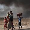 A newly displaced man carries two children at a check point in Qayyara, south of Mosul, Iraq. (file)