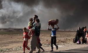 A newly displaced man carries two children at a check point in Qayyara, south of Mosul, Iraq. (file)