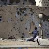 لیبیا کے شہر سرت میں بمباری کا نشانہ بنے والی ایک عمارت کے پاس سے ایک لڑکا بھاگتے ہوئے گزر رہا ہے۔