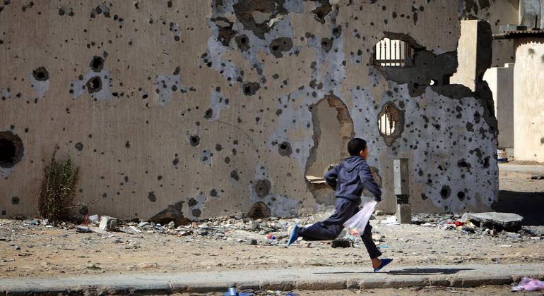 Un niño corre frente a edificios dañados por los bombardeos en la ciudad libia de Sirte.