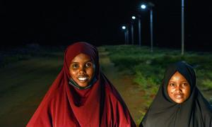 Iftin and Aminaa stand near the solar lights that now allow dozens of girls to walk safely to evening classes. 