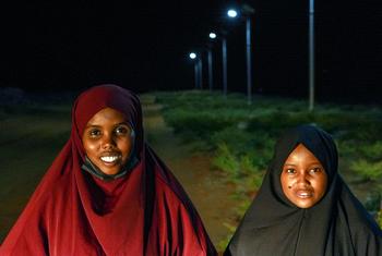 Iftin and Aminaa stand near the solar lights that now allow dozens of girls to walk safely to evening classes. 