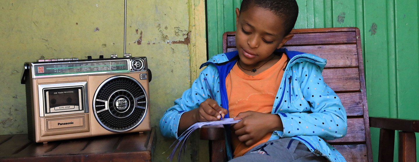 A young boy in Ethiopia attends class at home, taking lessons via the radio, which are being broadcast across the country. 
