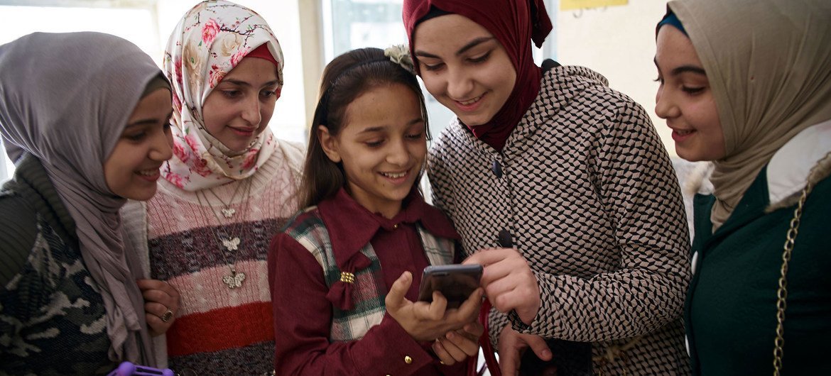 सीरियाई मूल की लड़कियाँ मिस्र में एक टैक्नॉलॉजी लैब के बाहर स्मार्टफ़ोन का इस्तेमाल कर रही हैं. 