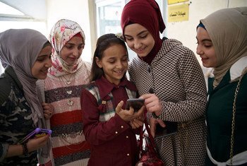 Syrian adolescent girls use a smartphone outside a technology lab in Damietta Governorate, Egypt.