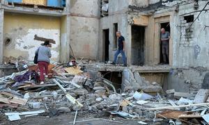 People survey the damage caused by a missile attack on a building in Kharkiv City, Ukraine.