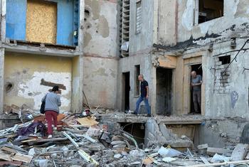 Des gens examinent les dégâts causés par une attaque de missile sur un bâtiment de la ville de Kharkiv, en Ukraine.