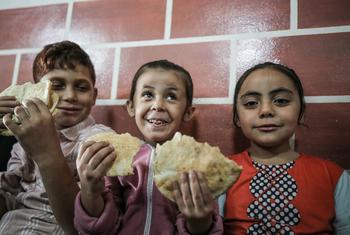 Niños refugiados en una escuela de UNRWA en Gaza disfrutan del pan distribuido por el PMA.