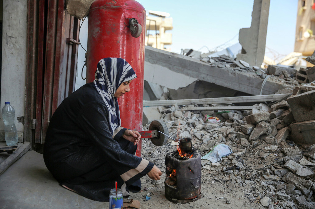 Une femme cuisine sur un réchaud en plein air à Gaza.