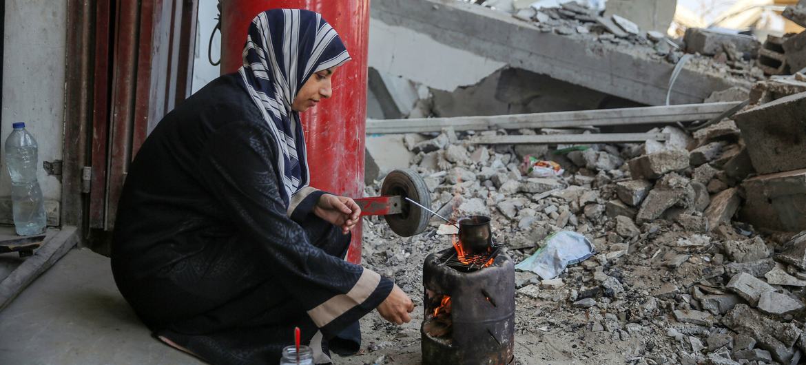  Uma mulher cozinha num fogão ao ar livre em Gaza