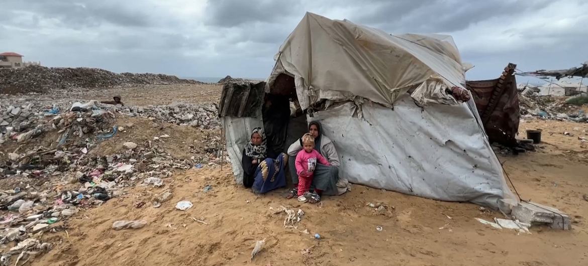 A family sits outside a makeshift shelter in Gaza.