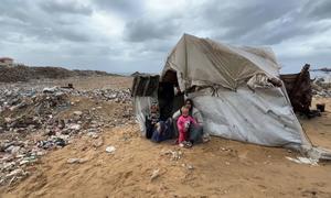 A family sits outside a makeshift shelter in Gaza.