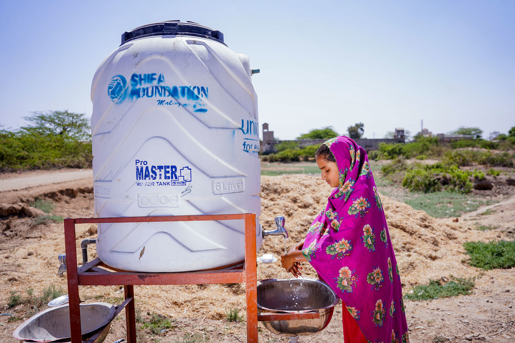 Une fillette de huit ans se lave les mains dans un réservoir d'eau installé par l'UNICEF.