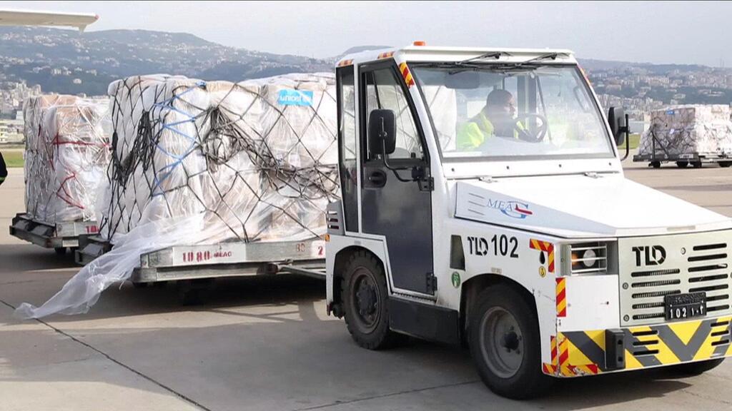 Paletas de suministros médicos que se descargan mientras la OMS y sus socios observan mientras comprueban la documentación del suministro.