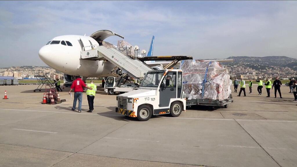 Des fournitures médicales sont déchargées d'un avion à l'aéroport international Rafik Hariri au Liban, avec des travailleurs et des véhicules d'aéroport visibles.