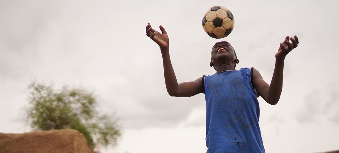 A ten-year-old boy plays football in an internally displaced camp in Abushok, Sudan. A ten-year-old boy plays football in an internally displaced camp in Abushok, Sudan.