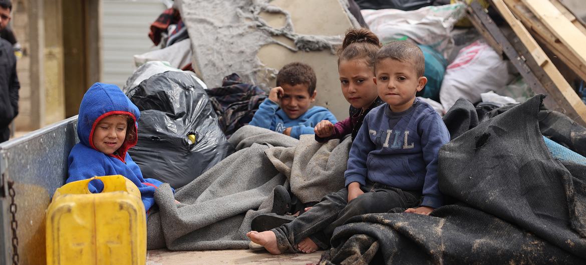 Children sit in the back of a truck as families are displaced again by the war in Gaza.