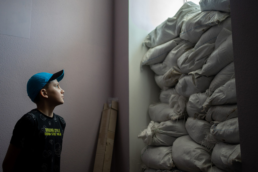 Un garçon à Kherson, en Ukraine, regarde par une fenêtre protégée par des sacs de sable.