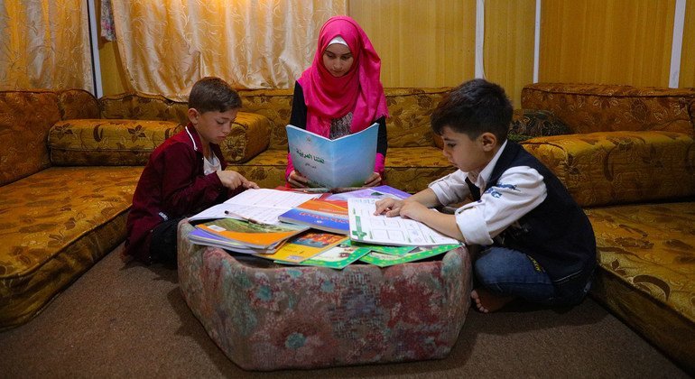 En un campo de refugiados en Jordania, una joven siria ayuda a su hermano menor y a un vecino a estudiar durante la pandeia.